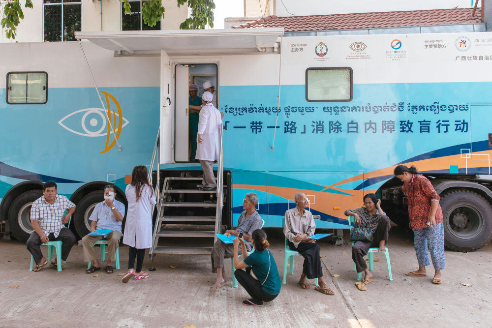 2019年3月15日，在柬埔寨磅湛省医院，白内障患者在“一带一路”消除白内障致盲行动医疗队的医疗车外等待接受手术治疗。